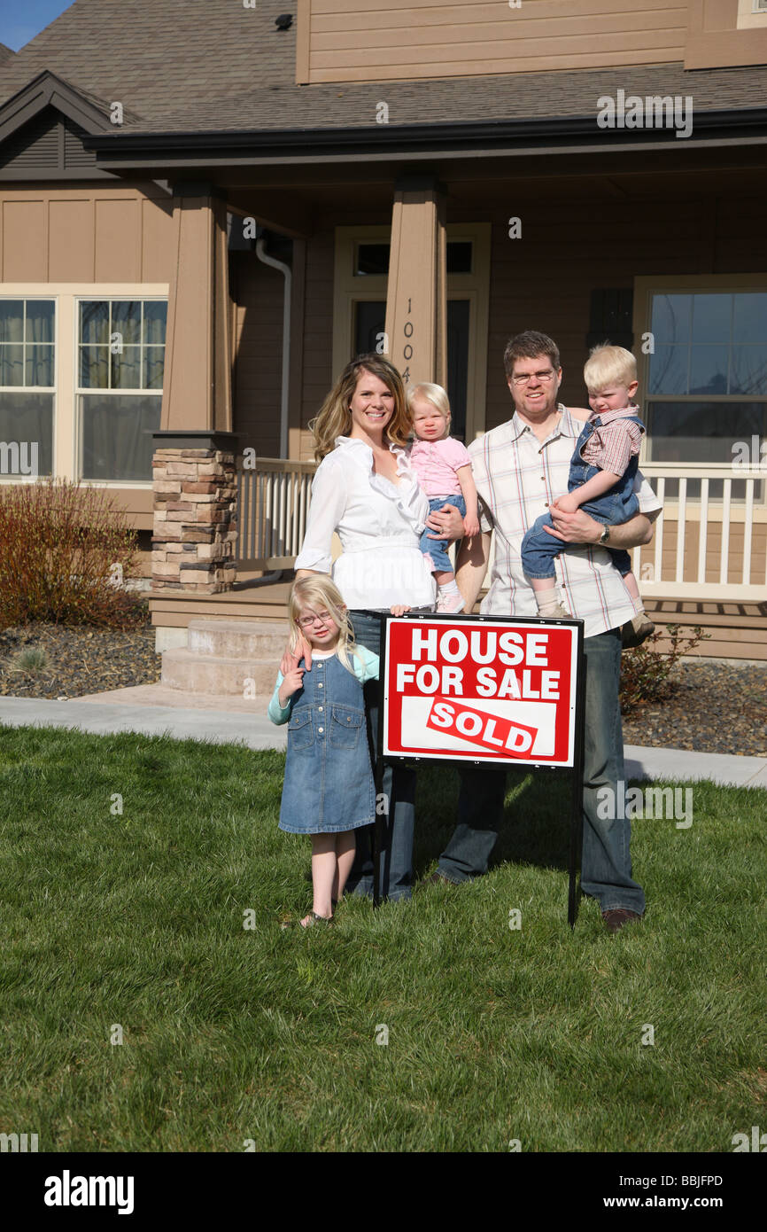 Family out in front of new home with SOLD sign Stock Photo