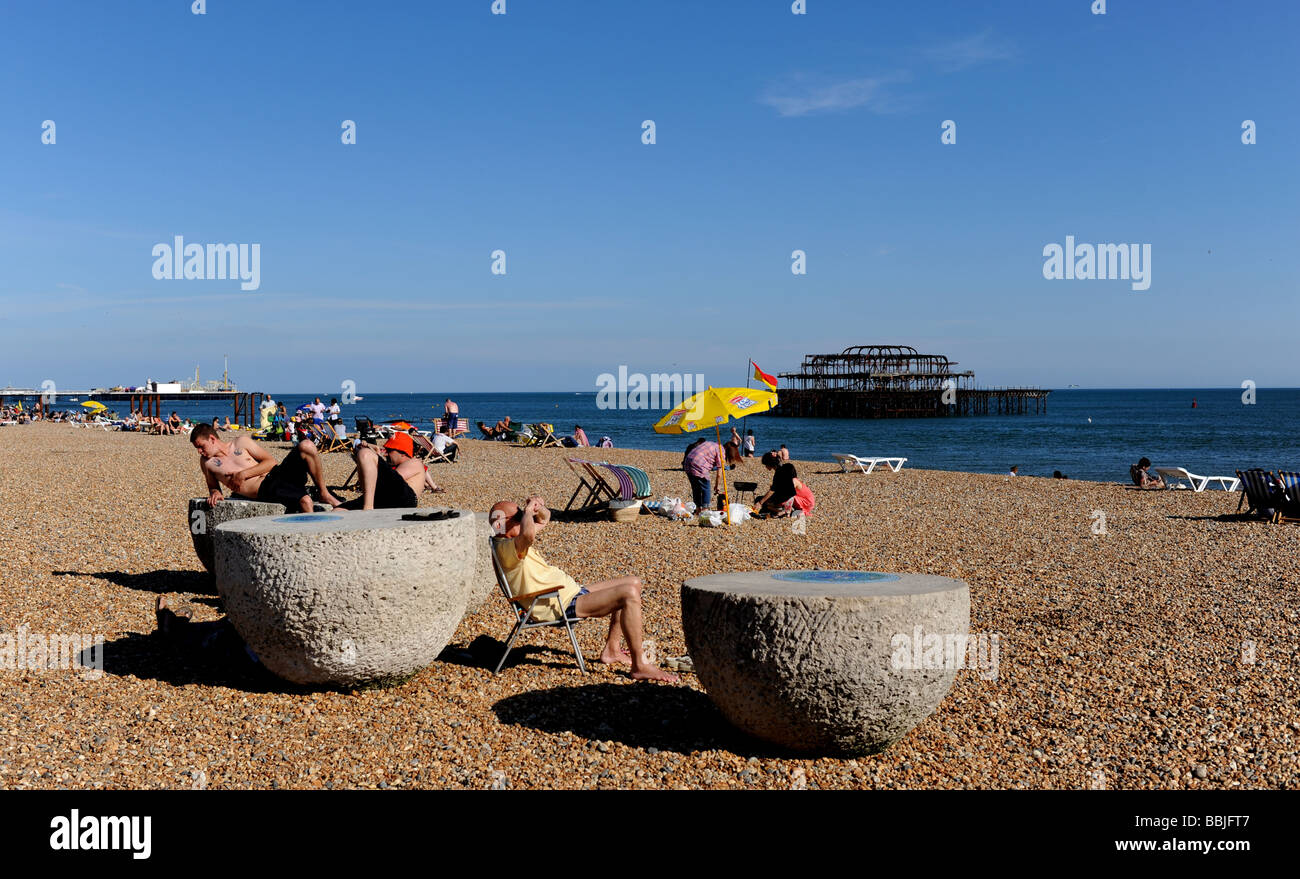 Sunbathing on Brighton beach by the West Pier , Sussex , England UK Stock Photo
