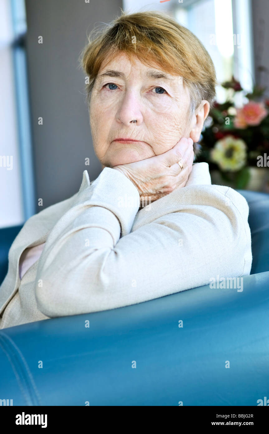 Sad elderly woman sitting on a couch indoors Stock Photo - Alamy