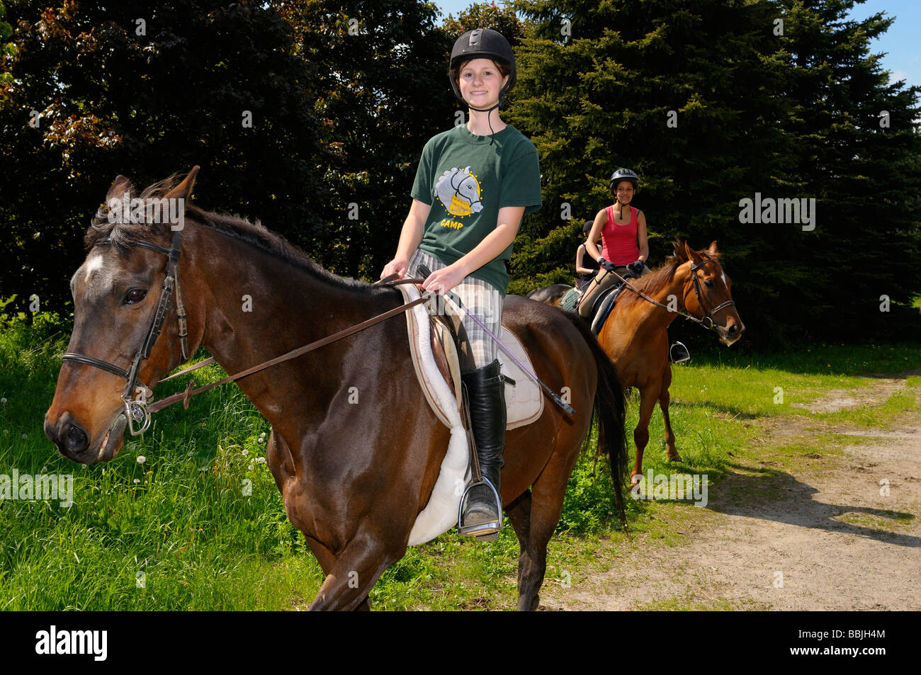 Three teenage girls riding thoroughbred horses after a trail ride hack in the country Ontario Stock Photo