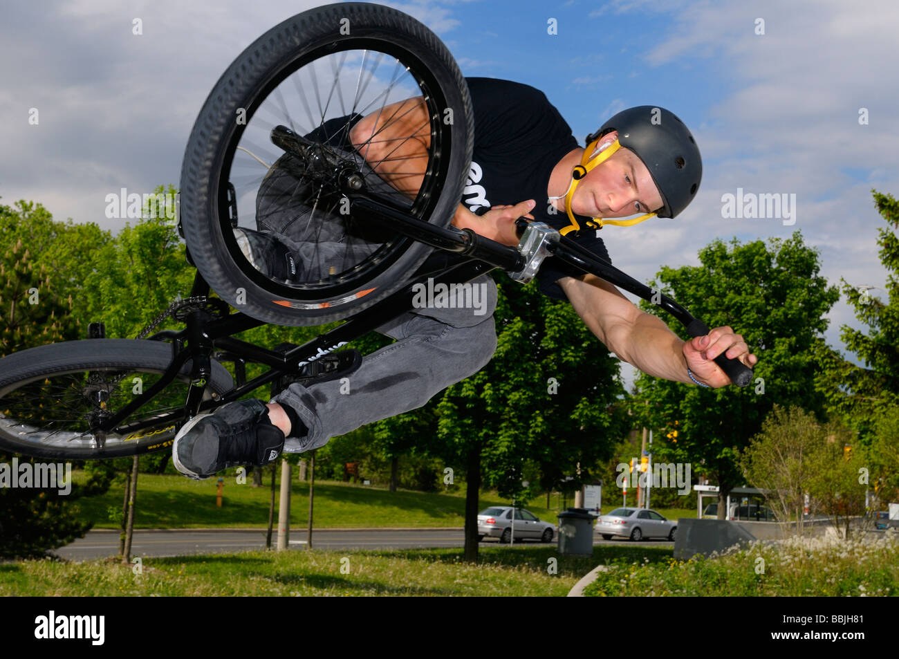 Airborne urban BMX bike rider in an Air Out Tabletop over local traffic at a Toronto city skatepark Stock Photo