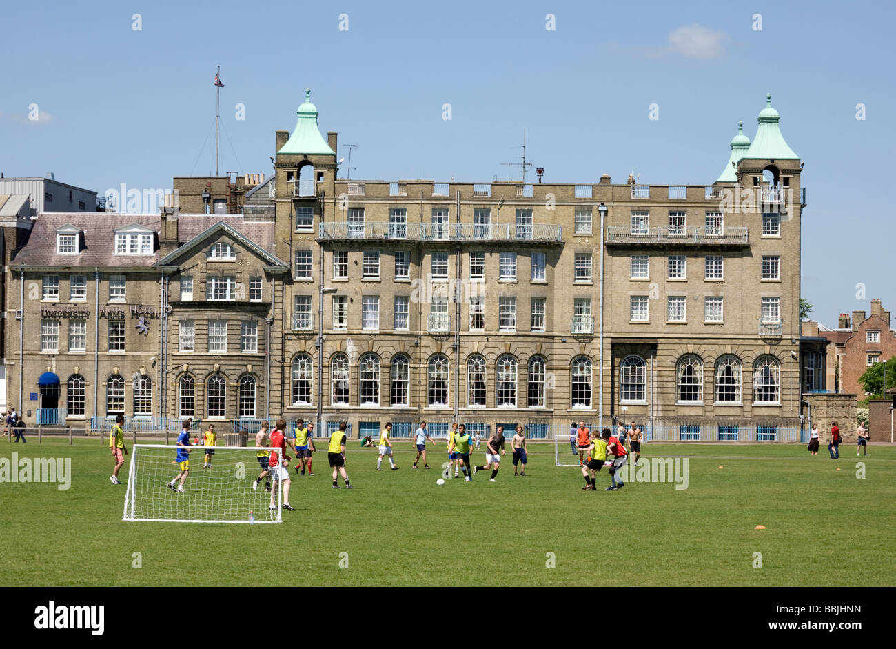 Teenagers playing football in front of the University Arms Hotel on Parkers Piece, Cambridge, UK Stock Photo