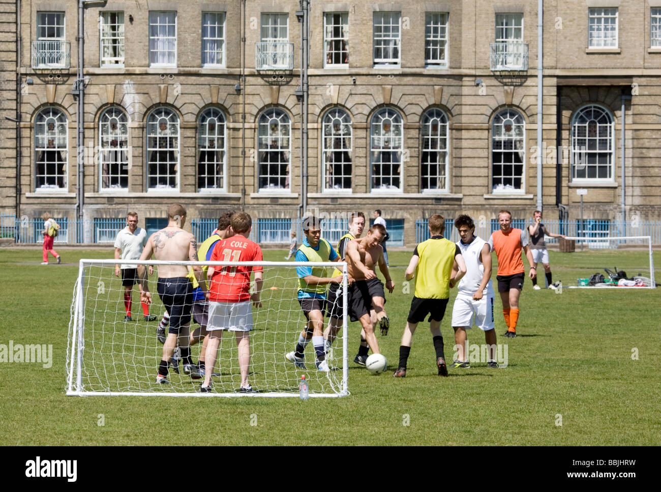 Teenagers playing football in front of the University Arms Hotel on Parkers Piece, Cambridge, UK Stock Photo