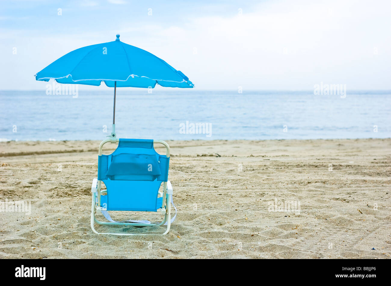 Blue beach chair overlooking empty ocean on beach Stock Photo