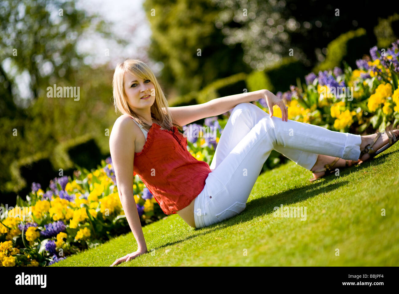 A young woman sits in the park and enjoys the warm hot summer weather. Stock Photo