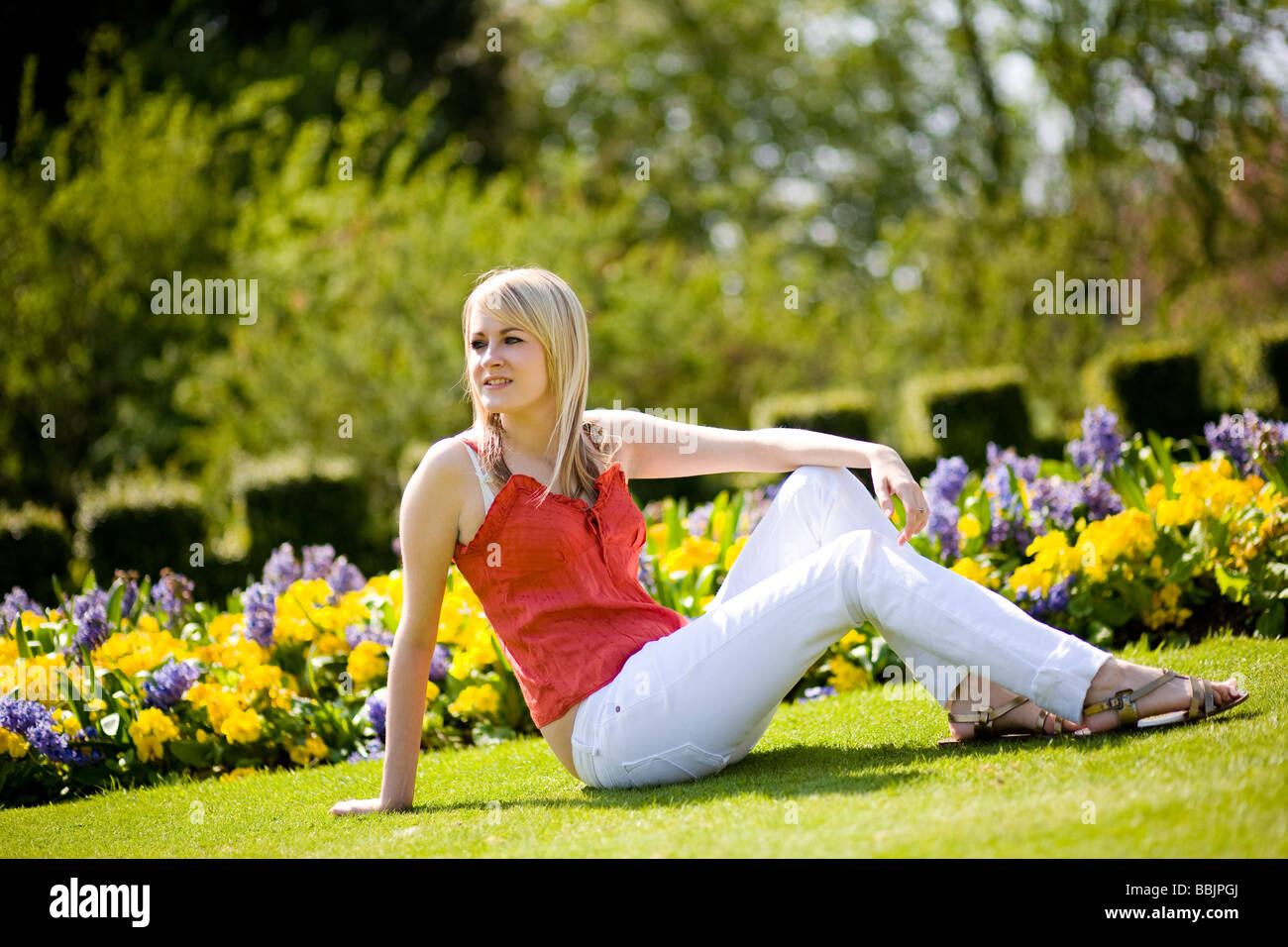 A young woman sits in the park and enjoys the warm hot summer weather. Stock Photo