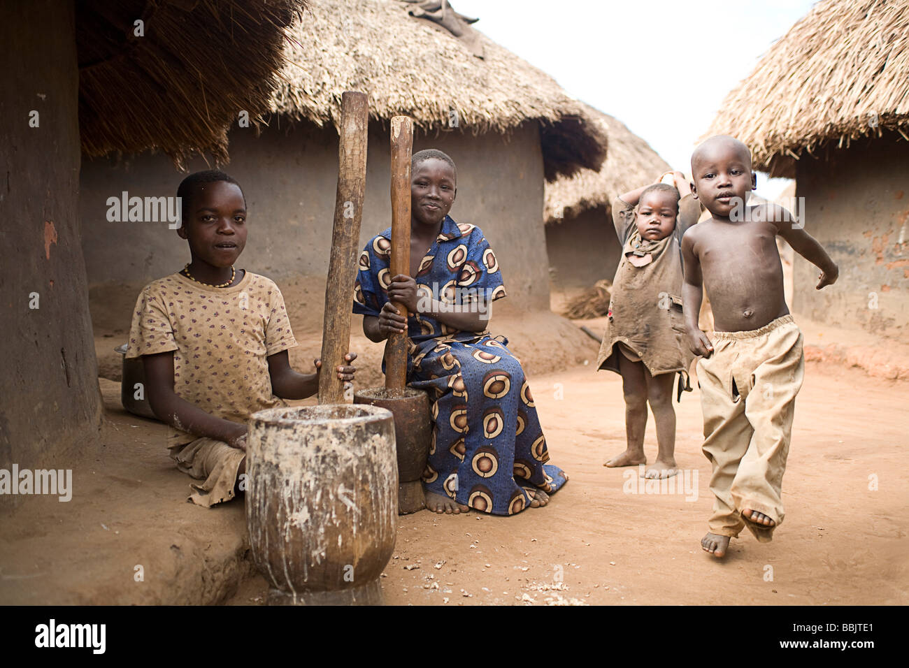 Koro-Abili IDP Camp, Gulu, Uganda; Family sitting next to mud huts Stock Photo
