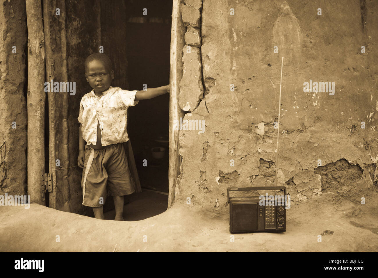 Koro-Abili IDP Camp, Gulu, Uganda; Young boy standing in doorway of mud hut Stock Photo
