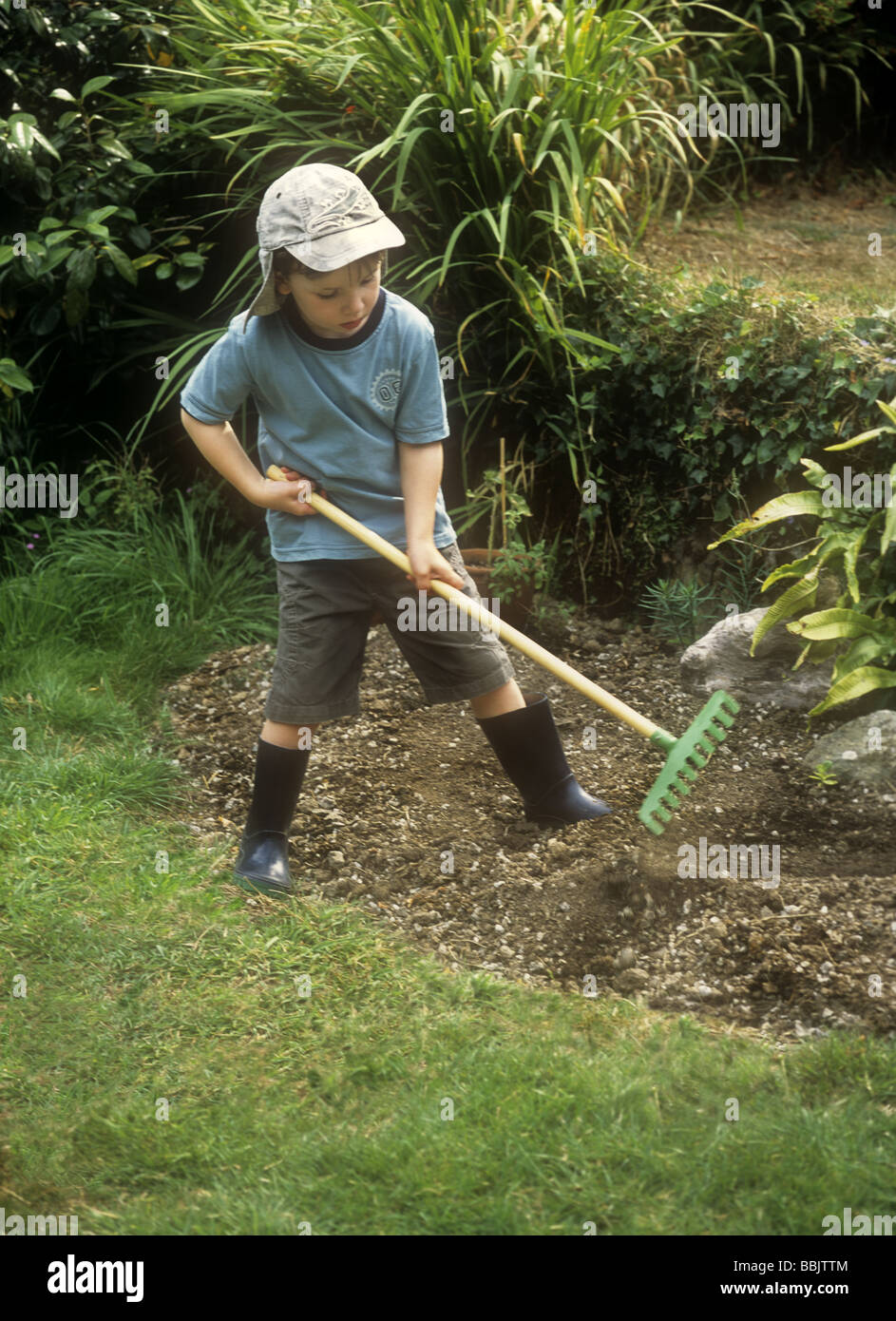 Young boy playing with a rake in a garden Stock Photo - Alamy