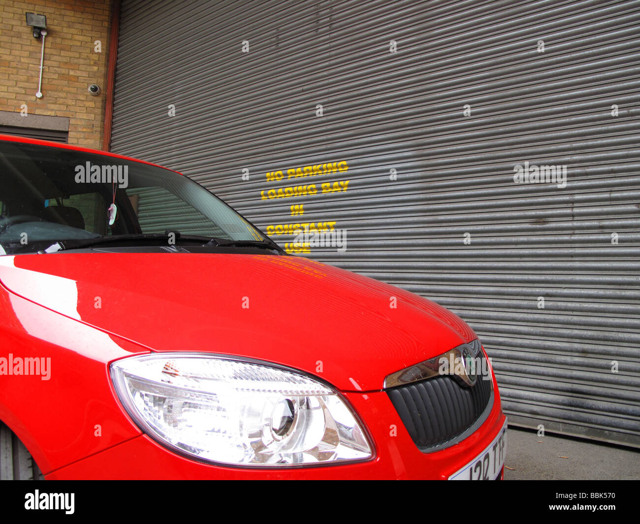 A Car Parked across a loading bay next to a No Parking Sign Stock Photo