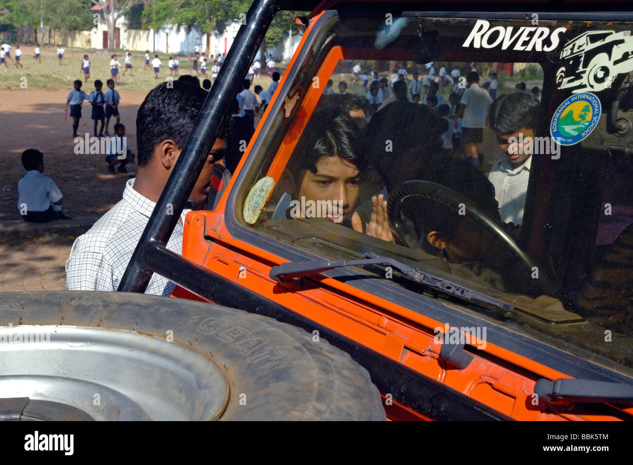 Schoolboys admiring a Land Rover Defender belonging to an aid worker. India, Kerala, Fort Cochin (Cochi, Kochi). Stock Photo