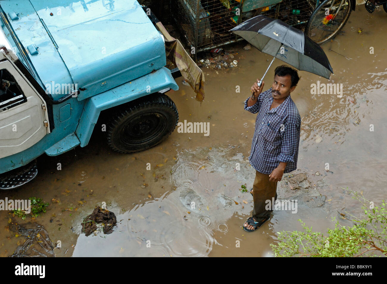 Standing in the rain in one of Chennai's many suburban slums. India, Tamil Nadu, Chennai (Madras).  No releases available.e Stock Photo