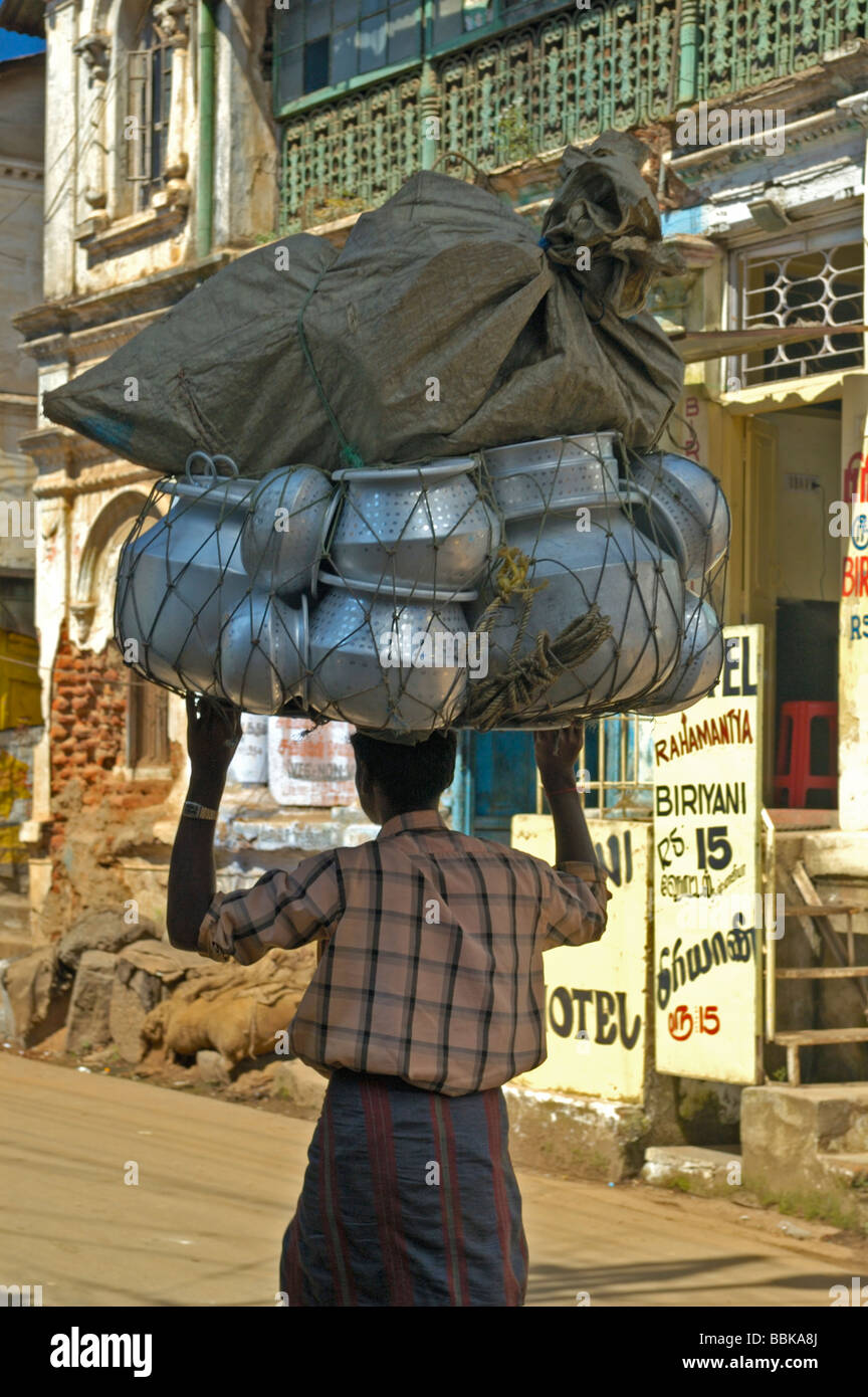 Indian man carrying a huge laod of aluminium pots on his head. India, Tamil Nadu, Ooty (Udhagamandalam). Stock Photo