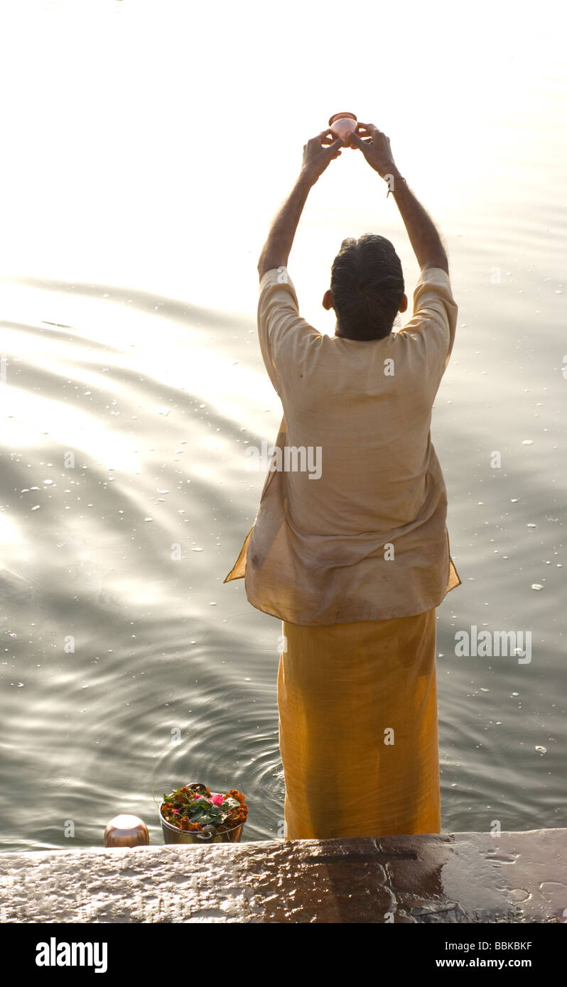 Holy man (brahmin) praying and making offering for river Ganges, holy for the Hindu. Bathing ghats, Varanasi, India. Stock Photo
