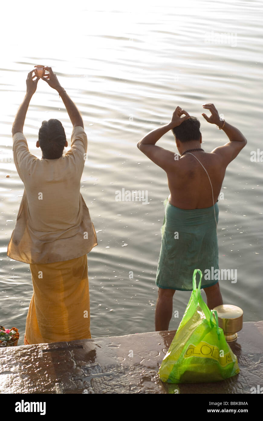Holy men (brahmins) praying and making offering for river Ganges, holy for the Hindu. Bathing ghats, Varanasi, India. Stock Photo