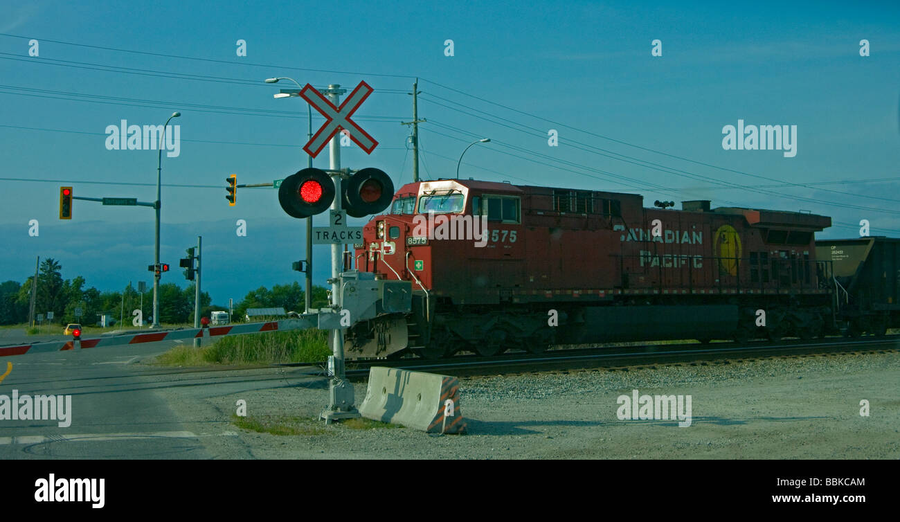 Railway crossing with red warning light ,gate and approaching Canadian