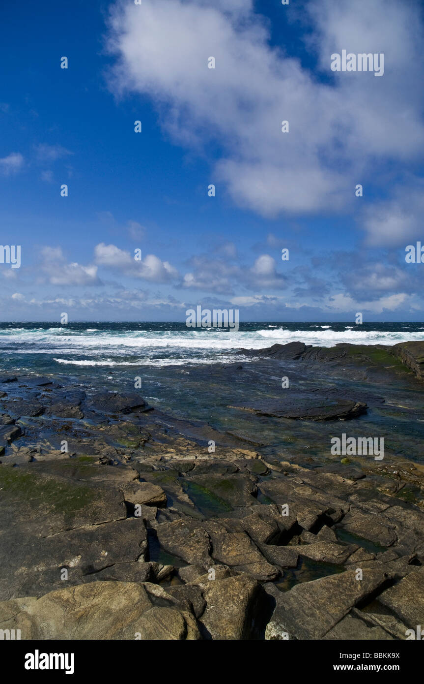 dh Bay of Ryasgeo NORTH RONALDSAY ORKNEY Blue skies white clouds surf waves coming shore on rocky beach Stock Photo