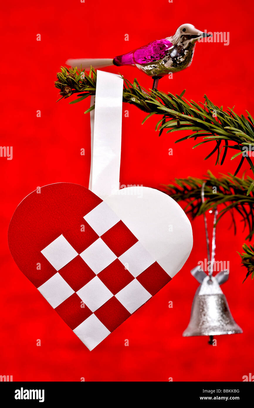 Glass bird and weaved heart on Christmas tree Stock Photo