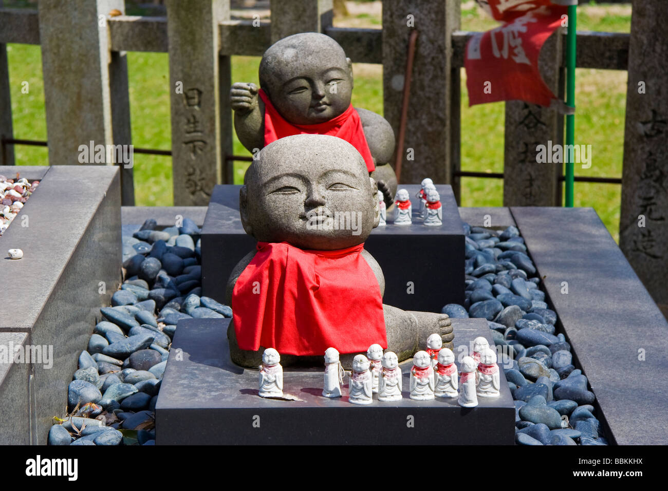 Two small Jizo statues with red bibs with many little ones in front at