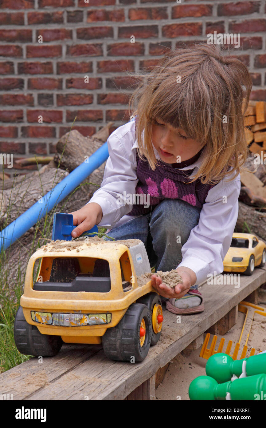 little girl playing with a toy car in a sandpit Stock Photo