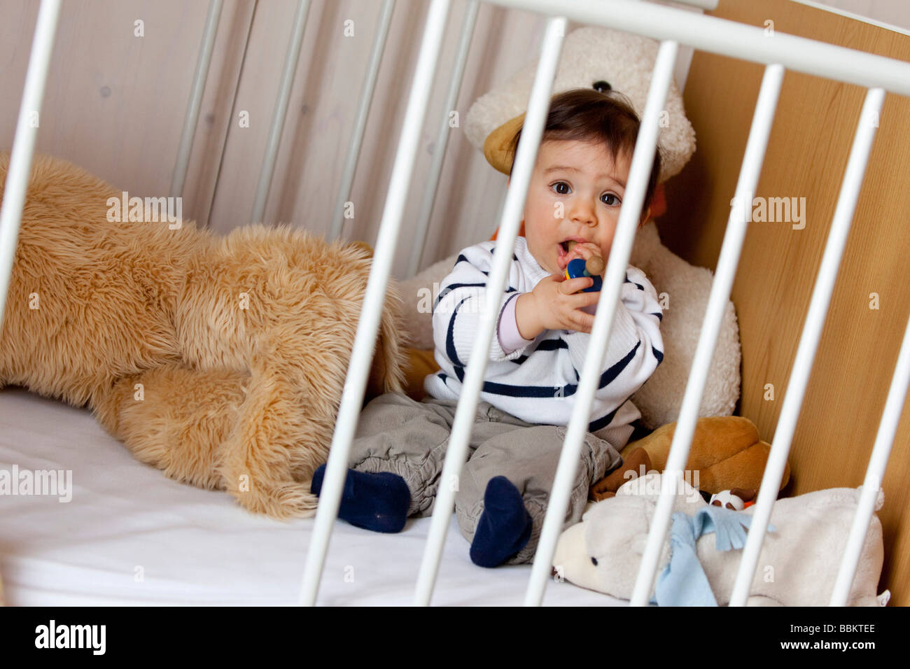 Nine-month-old baby sitting in his cot Stock Photo