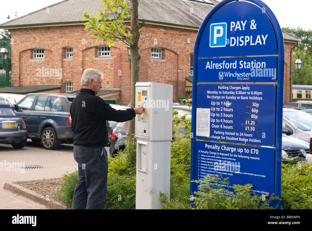 Motorist using pay and display parking machine, Alresford station, Hampshire UK. Stock Photo