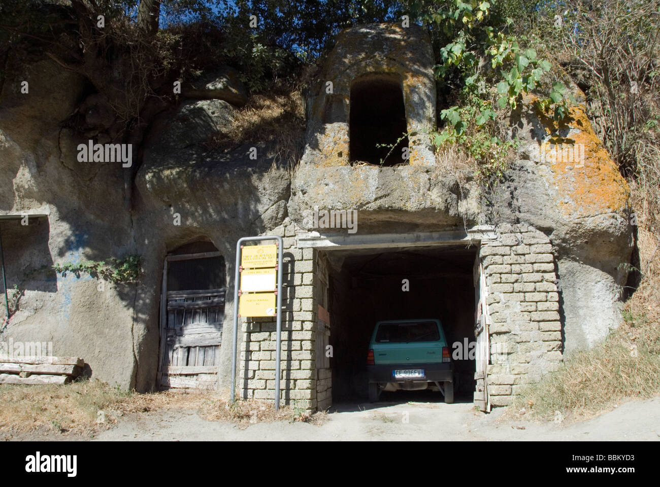 Garages and dwellings carved into tufa rock near the ruins of the Medieval castle of Vitozza in San Quirico, GR Stock Photo