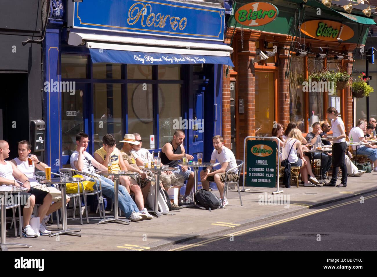 People enjoy warm summer day in sidewalk cafe bars West End London United Kingdom Stock Photo