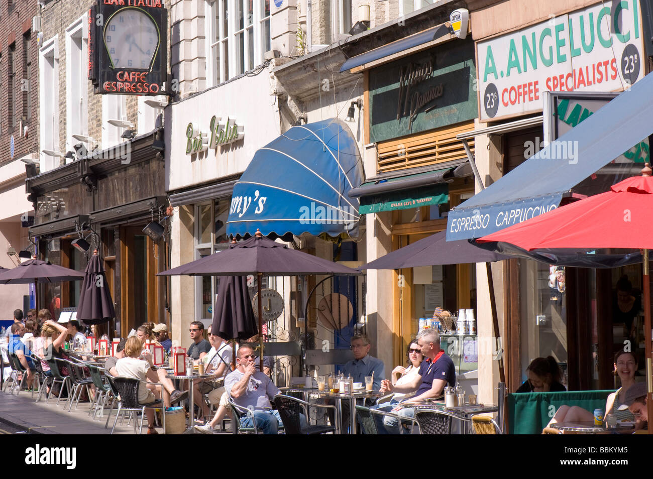 People enjoy warm summer day in sidewalk cafe bars West End London United Kingdom Stock Photo