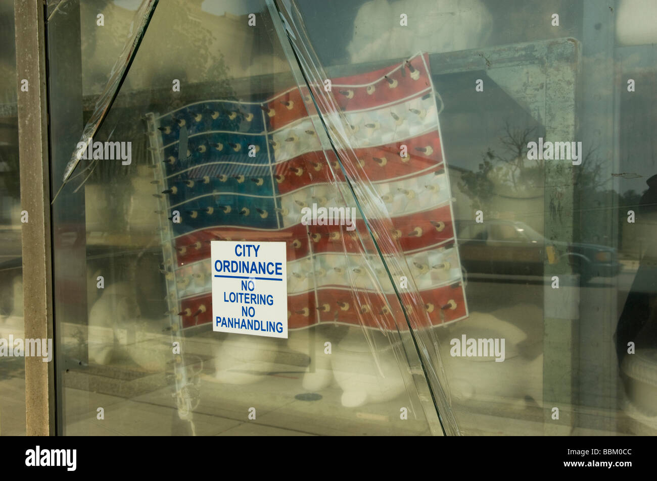 American flag in store window with sign City Ordinace no loitering or panhandling Stock Photo