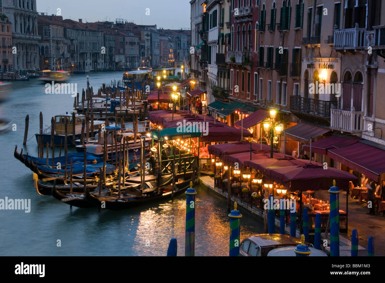 Restaurant seating and gondola moorings on the Grand Canal at night Riva del Vin Venice Italy Stock Photo