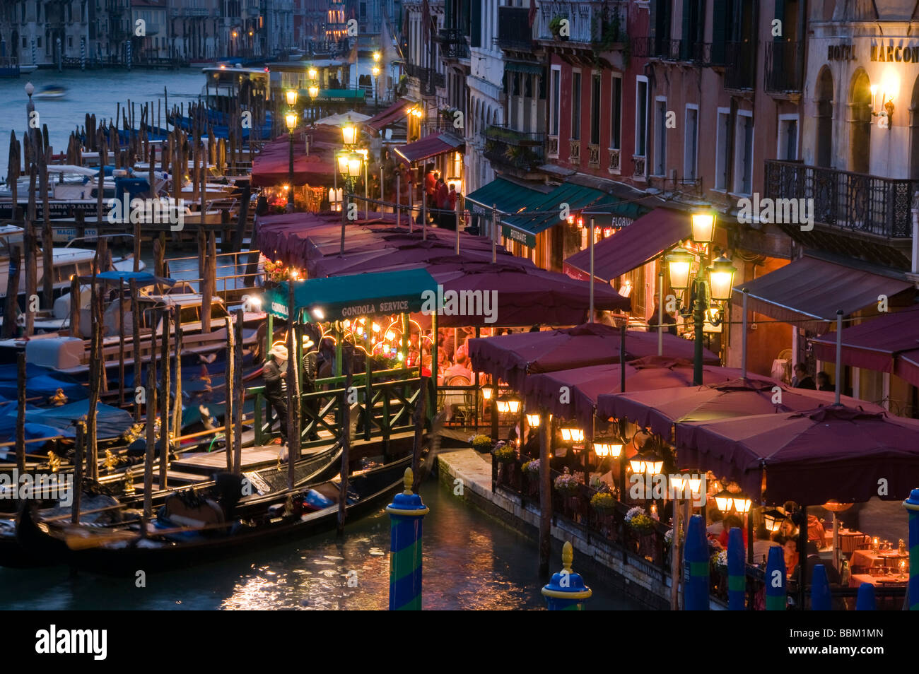 Restaurant seating and gondola moorings on the Grand Canal at night Riva del Vin Venice Italy Stock Photo