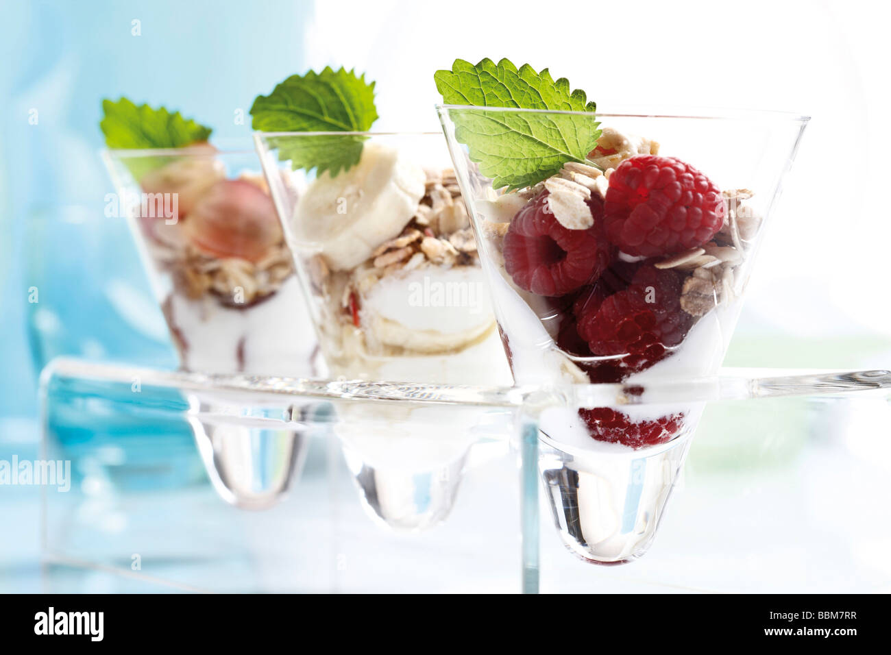 Muesli with yoghurt in a small glass jar, raspberries, sliced banana, grapes, mint leafs Stock Photo