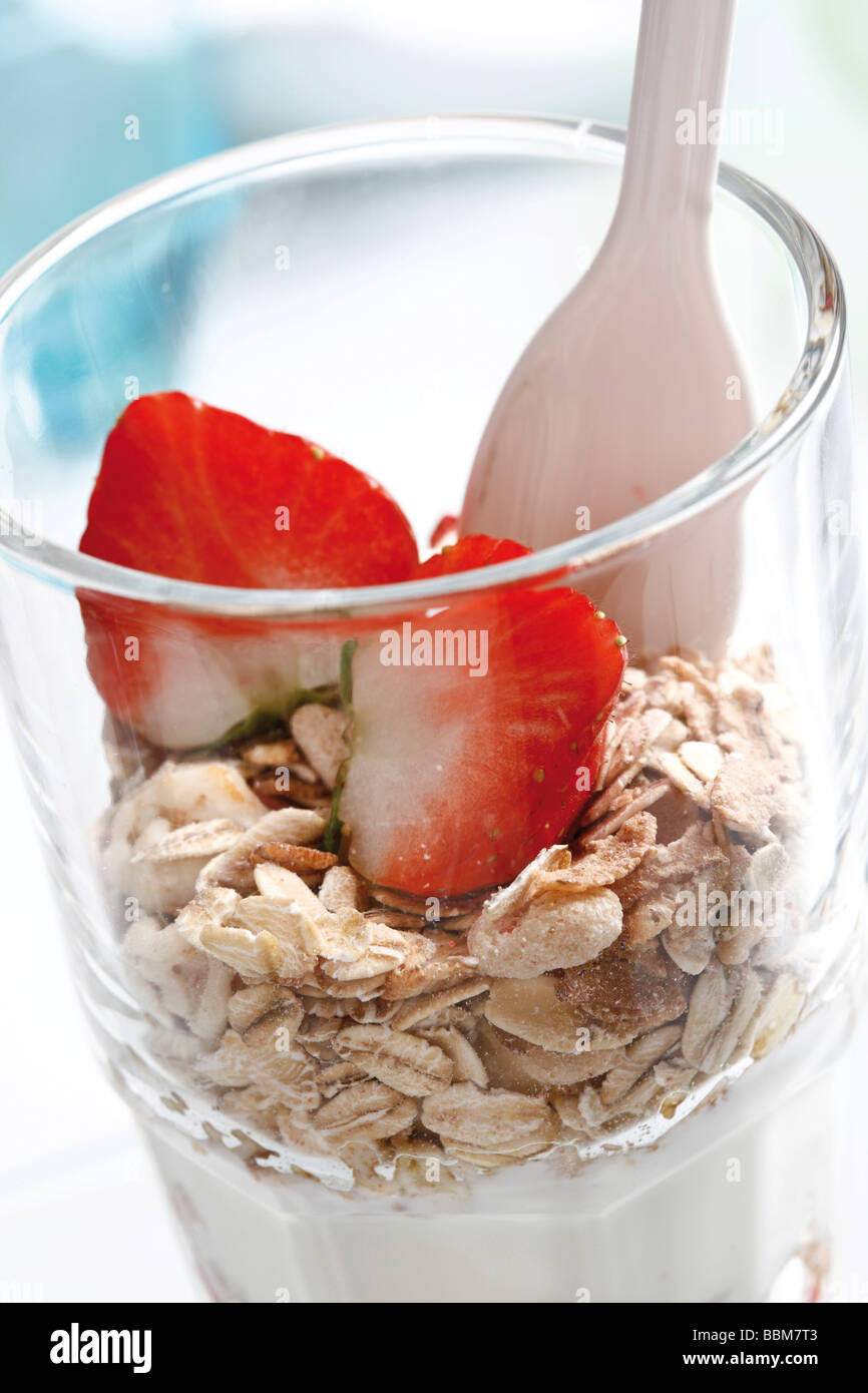 Muesli with yoghurt in a small glass jar, strawberries, yoghurt spoon Stock Photo