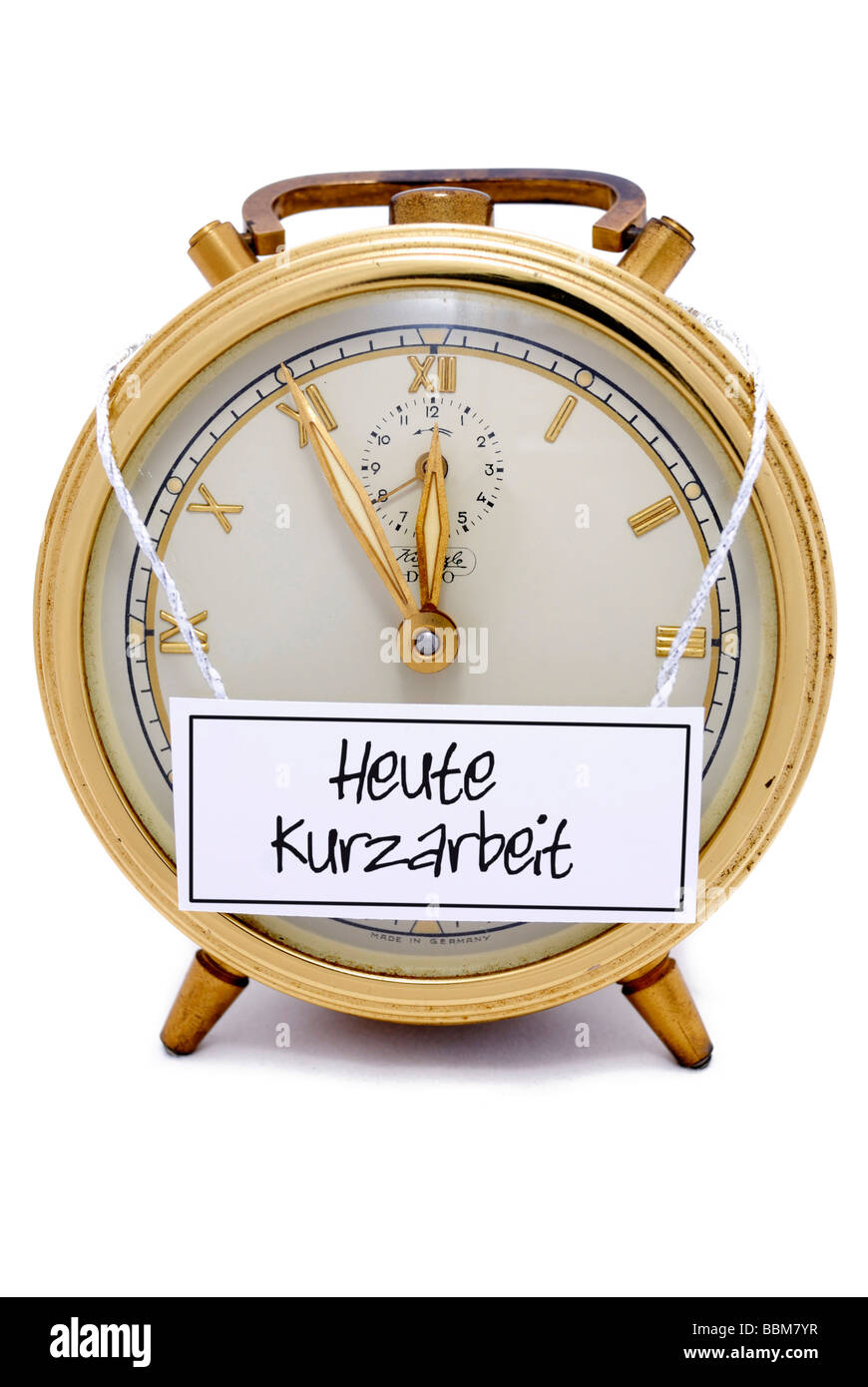Alarm clock, 5 to 12, 'Heute Kurzarbeit', German for: today short-time work, written on a sign Stock Photo