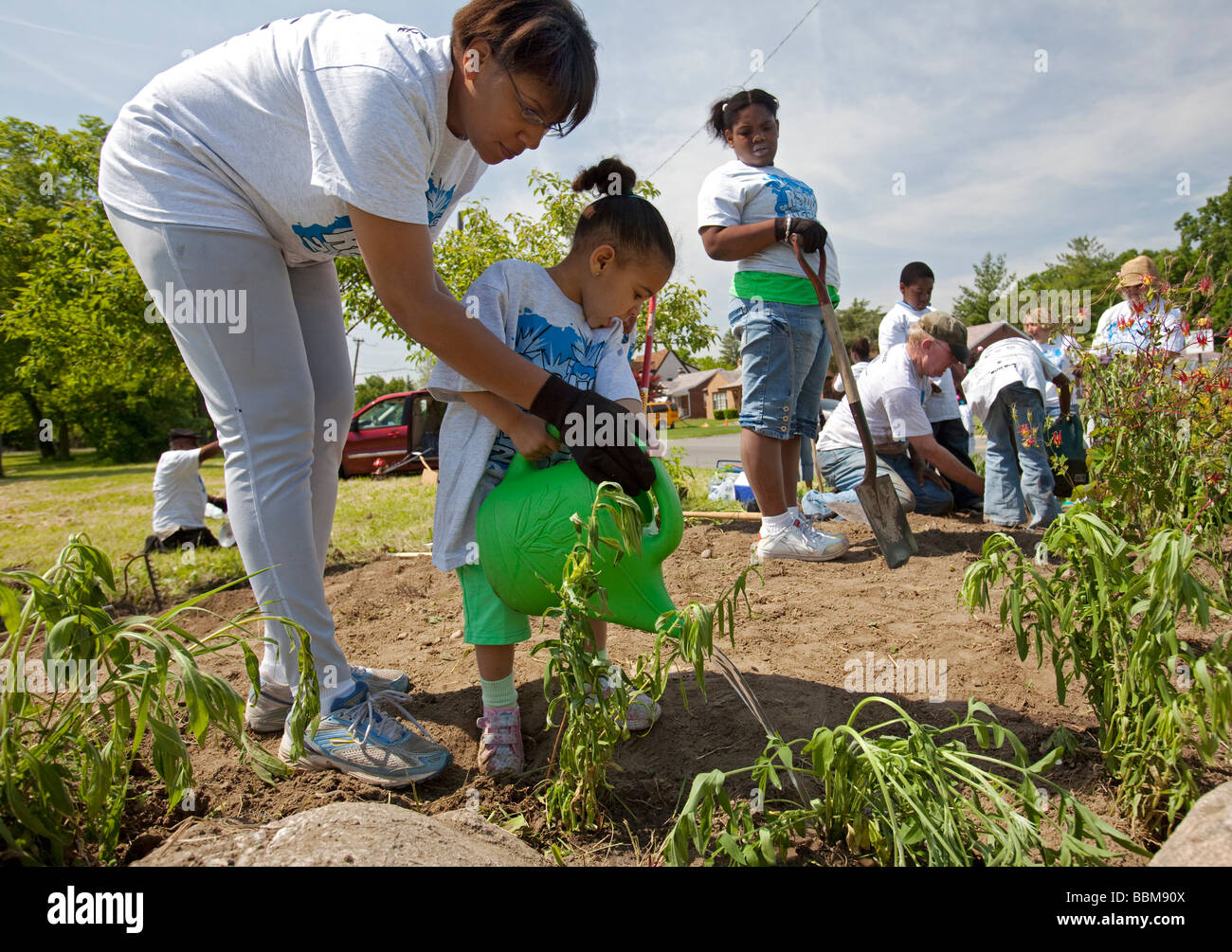 Detroit Michigan A mother helps her young child water plants planted by volunteers in Rouge Park as part of a park cleanup Stock Photo