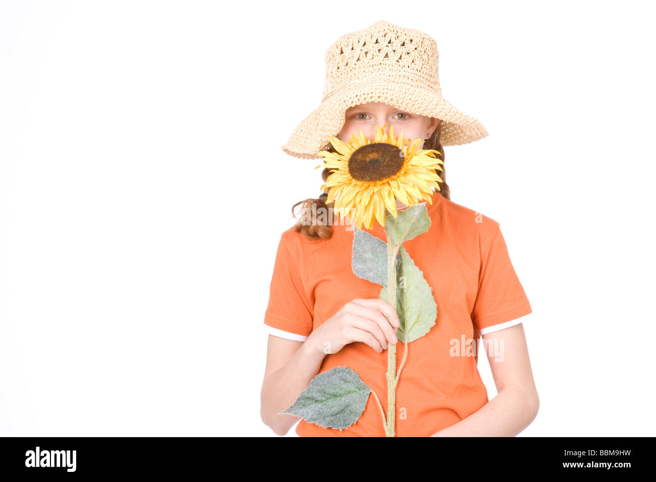 Red-haired girl with braids wearing a straw hat and holding a sunflower Stock Photo