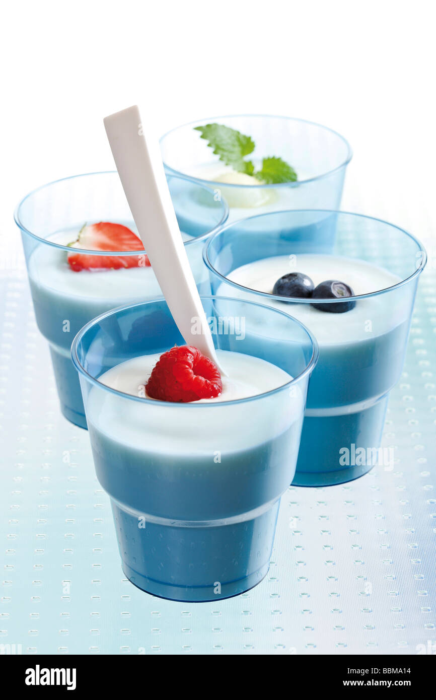 Four blue yoghurt cups with fruit, raspberry, strawberry, blueberries