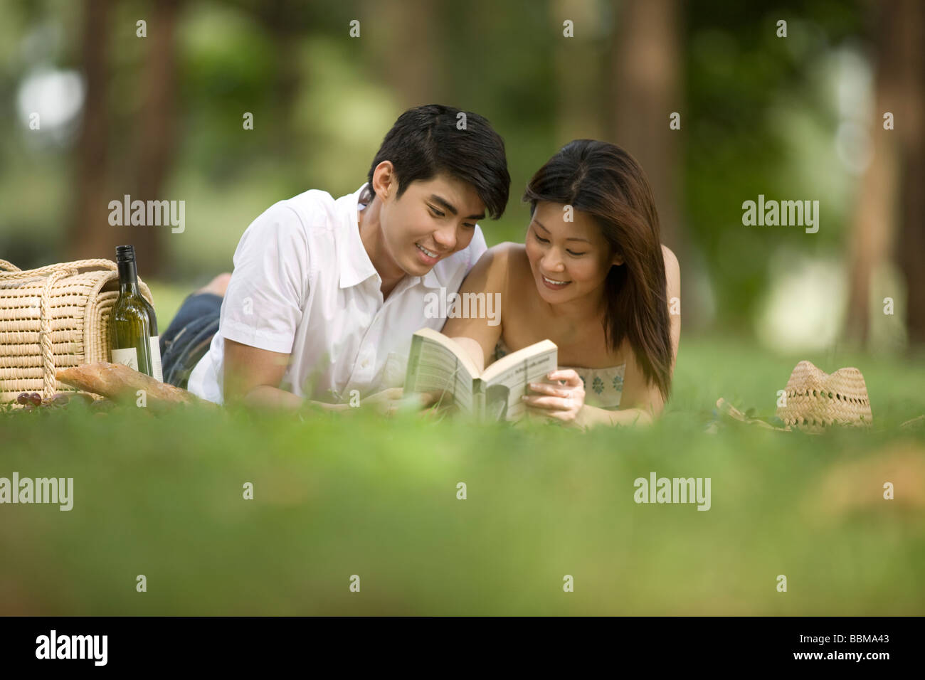 Young couple having picnic in the park, reading Stock Photo
