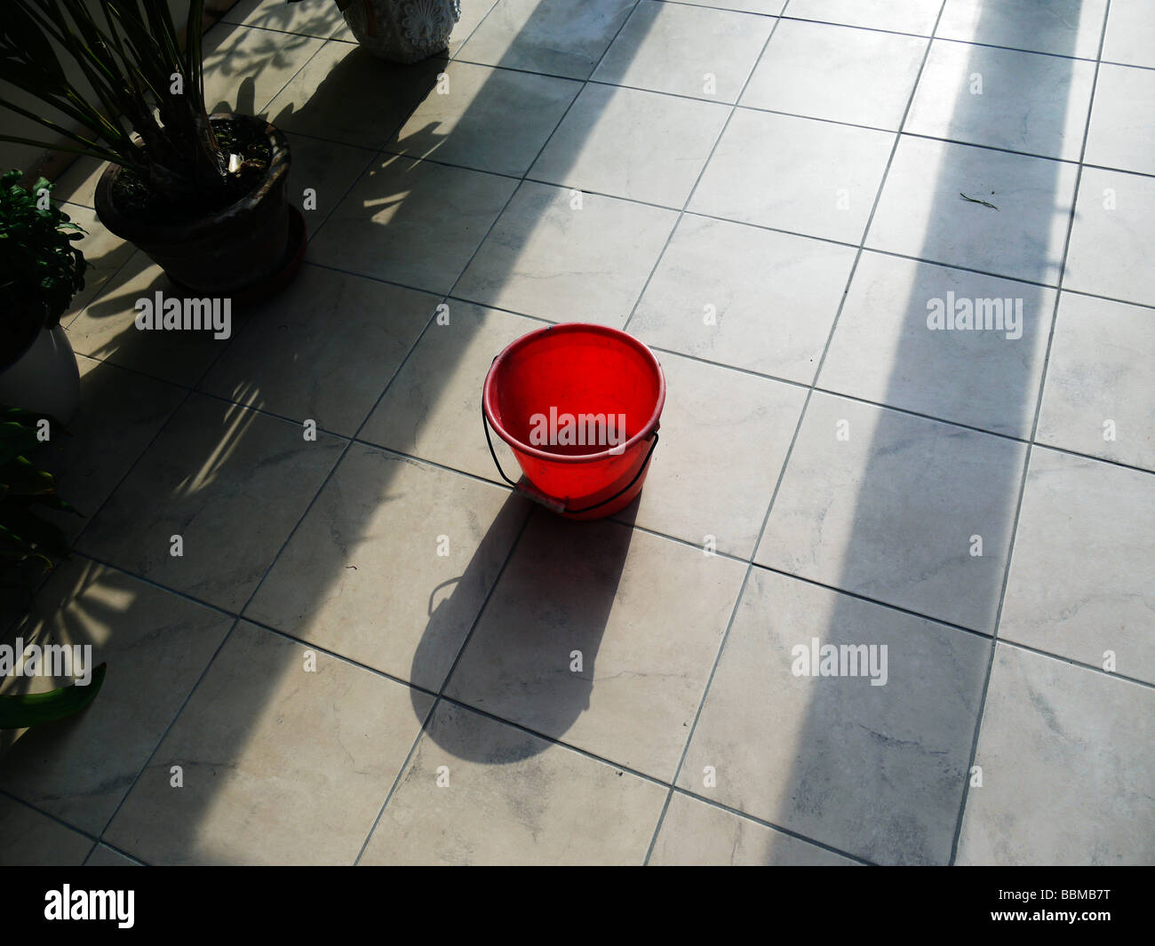 a red bucket on a tiled floor Stock Photo Alamy