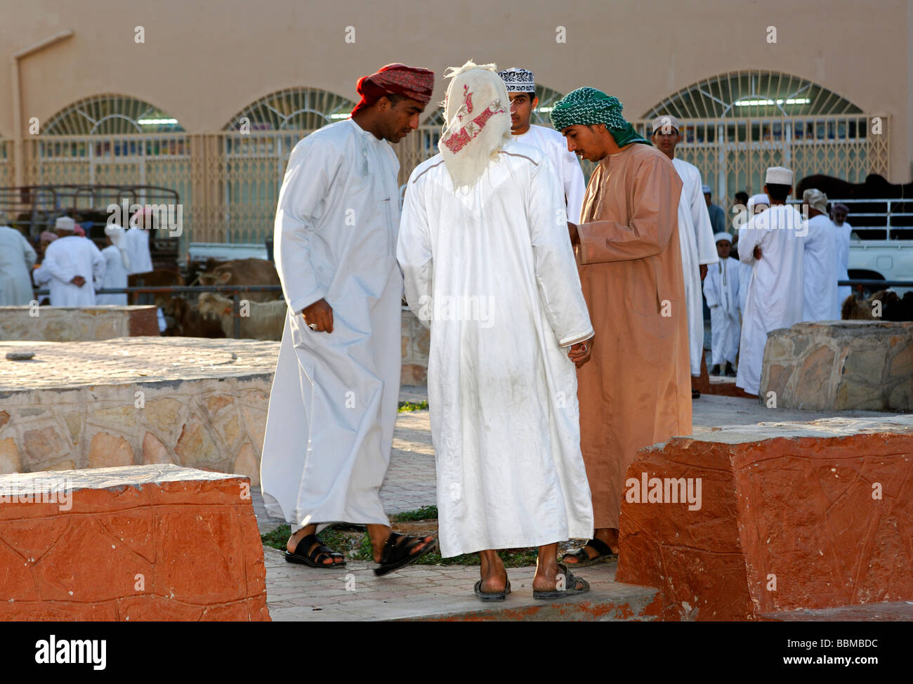 Local men wearing Dishdasha, the traditional Omani garment, on the grounds of the goat market, Nizwa, Sultanate of Oman Stock Photo