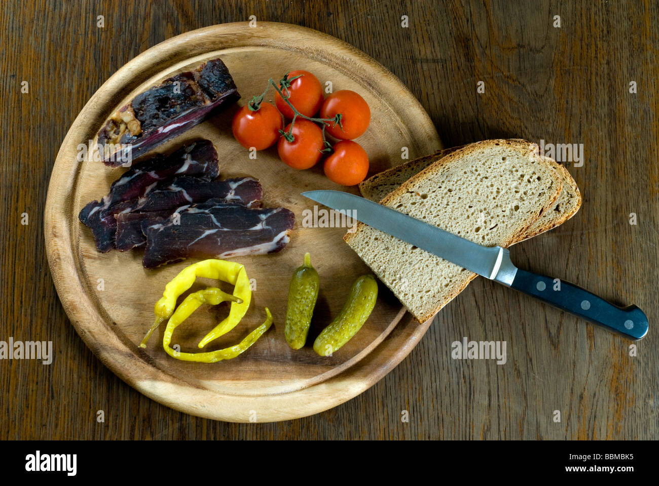 Snack with wild boar ham, tomatoes, cornicons, peppers and bread Stock Photo