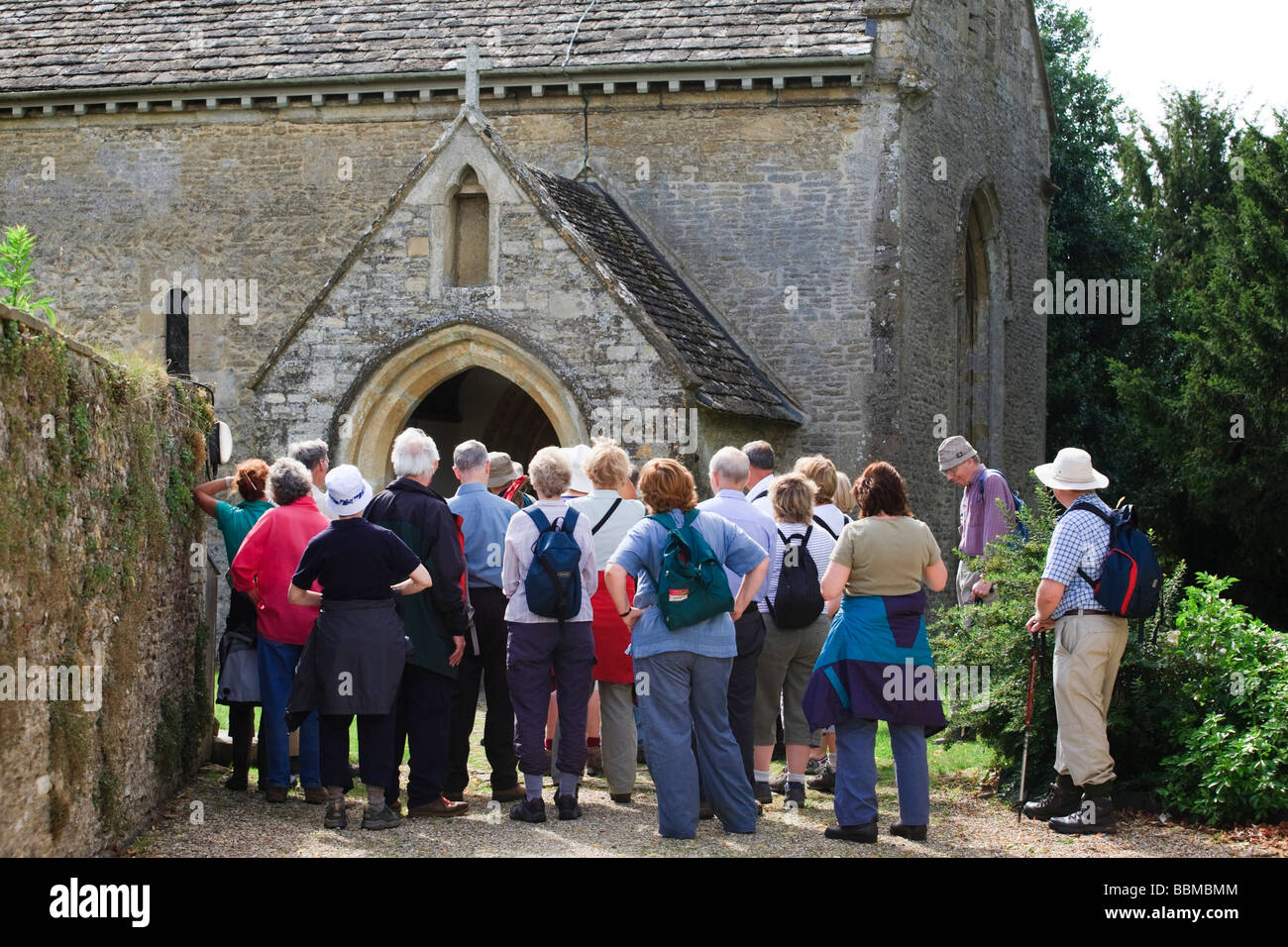 A group of retirees looking at an historic church in the Cotswolds, Eastleach Turville, Gloucestershire, UK Stock Photo