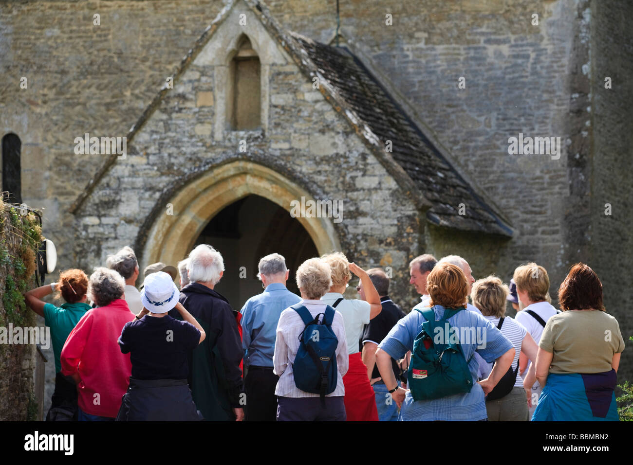 A group of retirees looking at an historic church in the Cotswolds, Eastleach Turville, Gloucestershire, UK Stock Photo