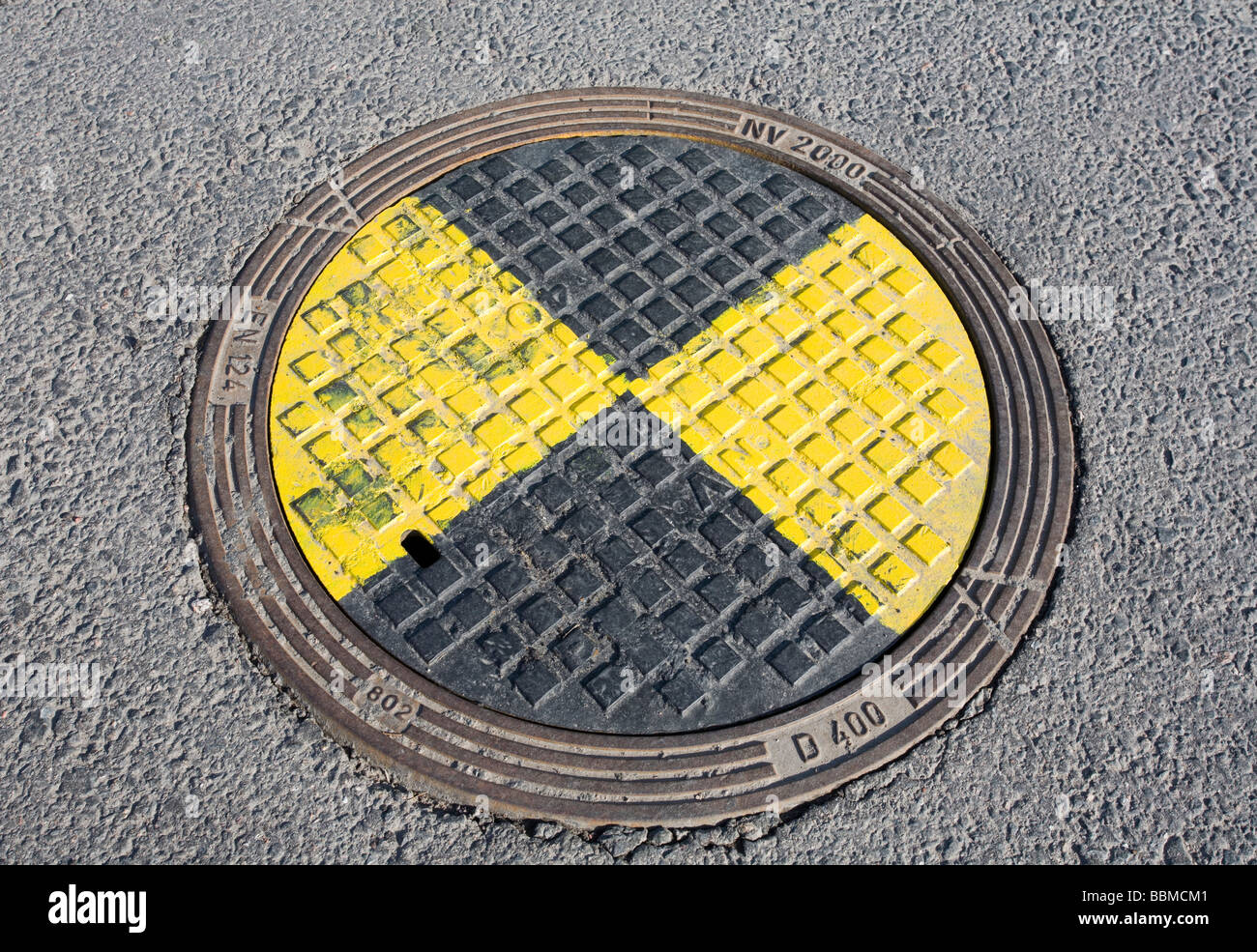 man hole sewer cover painted yellow and black Stock Photo