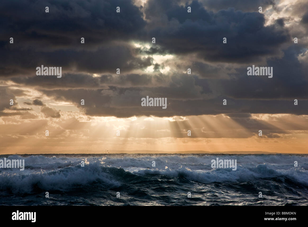 Australia, Victoria.  In the late afternoon, the  sun breaks through threatening clouds over the Bass Straits. Stock Photo