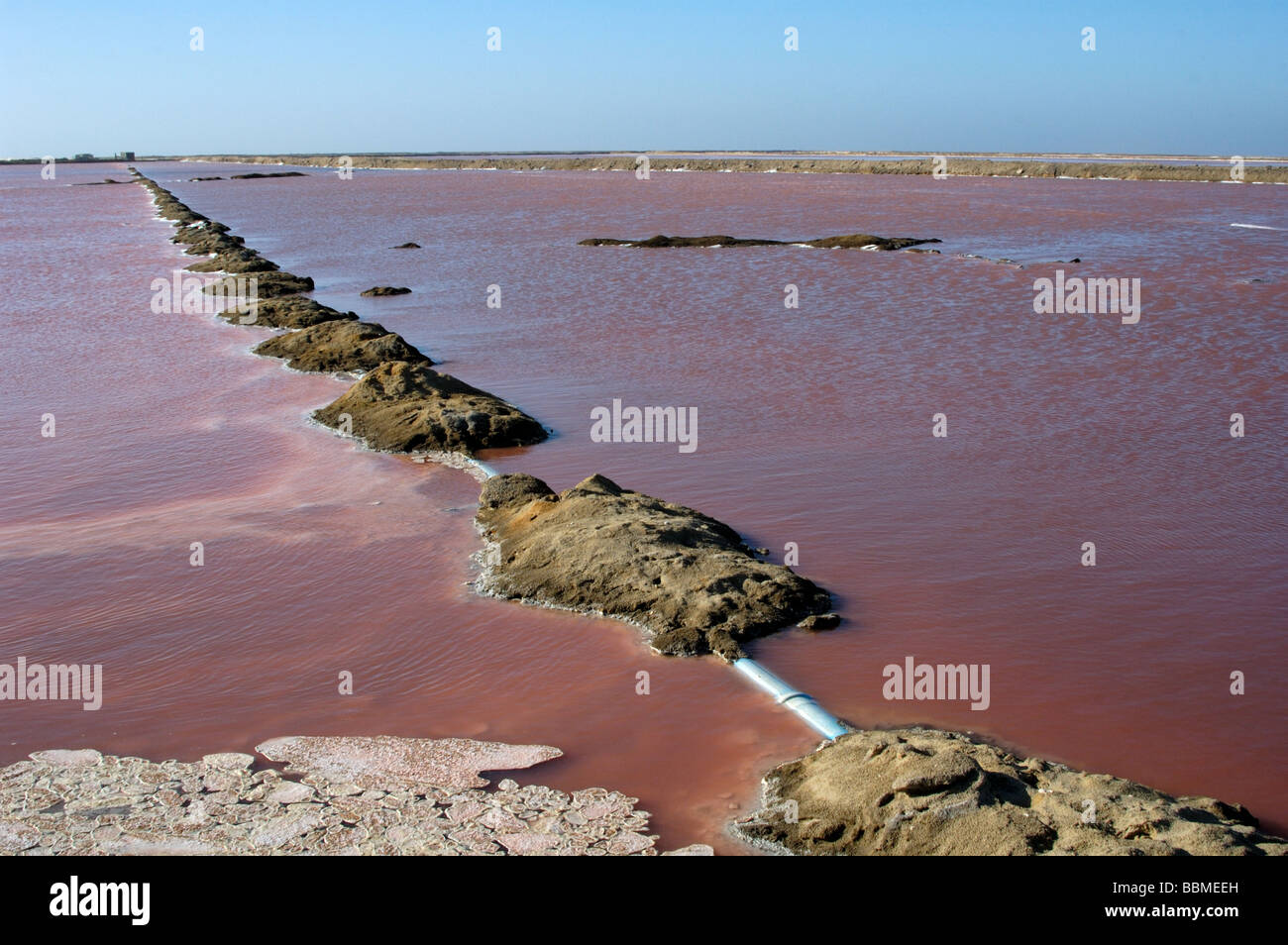 Sea water evaporating in pans leaves crystalline salt behind Stock