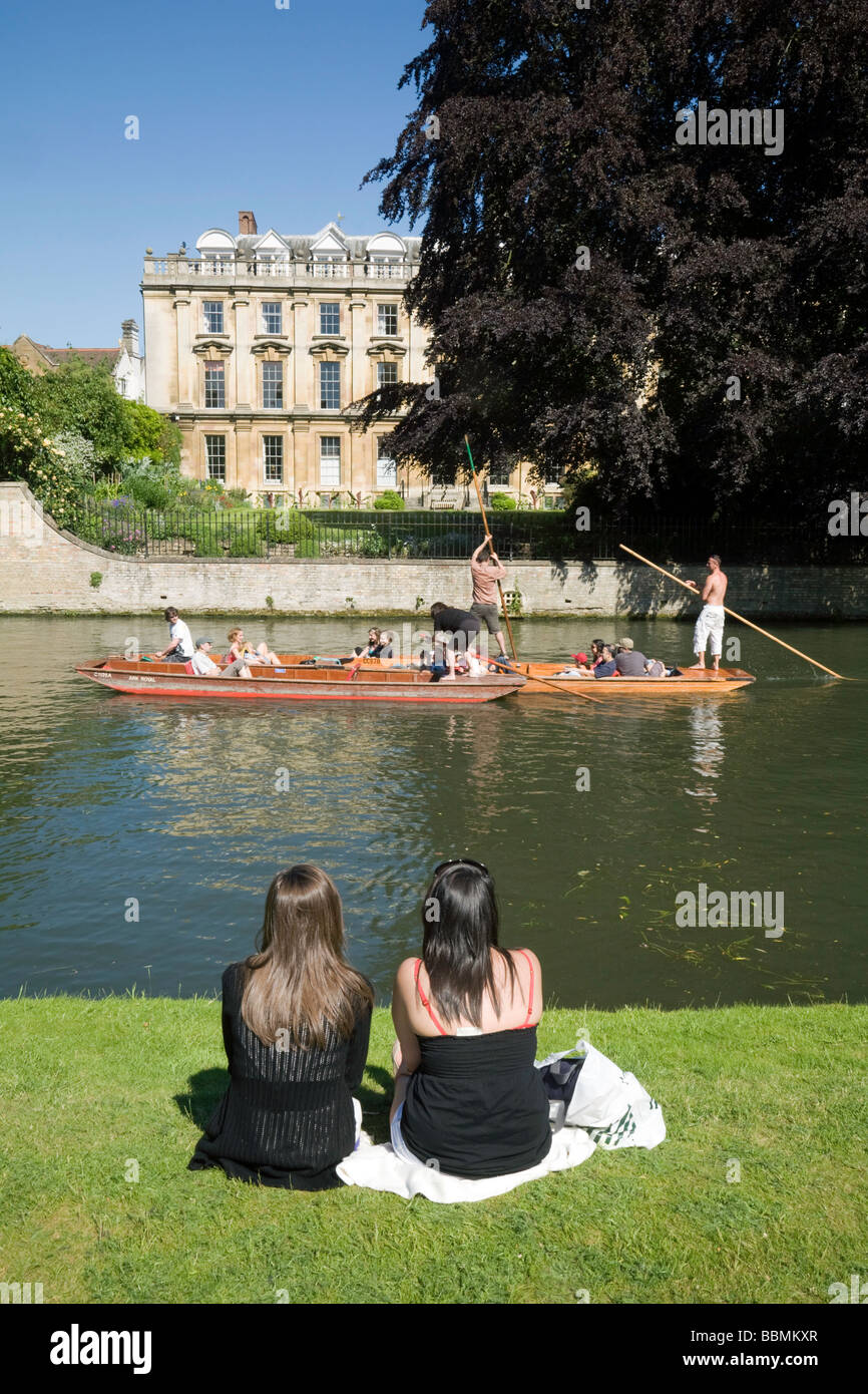 People sitting on the banks of the River Cam at Clare College, Cambridge, watching the punting on a summers day Stock Photo