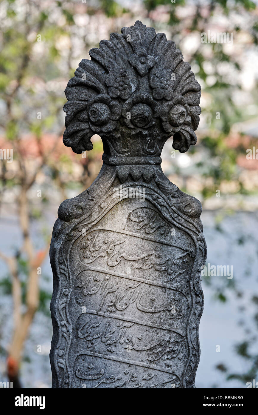 Traditional Muslim tombstone on a woman's grave with flowers for the