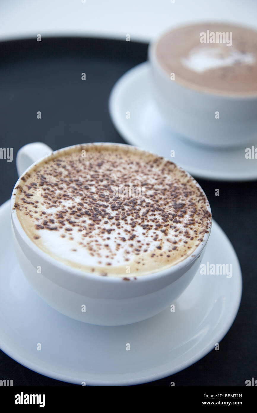 A cappuccinno coffee and a hot chocolate on a black tray Stock Photo